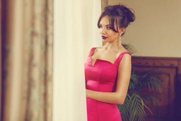 Elegant young woman in evening dress posing in luxury interior. Fashion shot