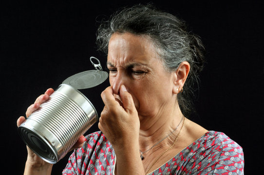 Femme sentant une bo&icirc;te de conserve qui pue