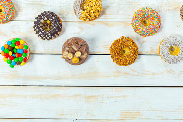 Collection of tasty donuts on white wooden board
