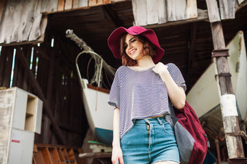 Funny Hipster Girl in old boat garage in island, Lots of boats.Trendy Casual Fashion Outfit in summer,spring. Toned Photo.