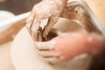 Making ceramics pot dirty hands close-up. Top view on almost ready clay pot and hands, finishing it. Potter finishing clay pot in special trough