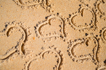 Group of many love heart symbols on sunny sandy beach background. Lovely holiday vacation greeting card.