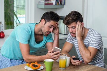 Obraz na płótnie Canvas Frustrated male friends using phone 