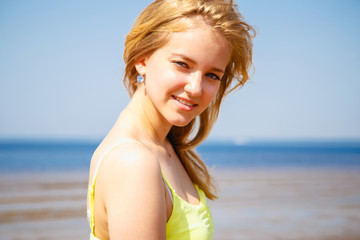 Fototapeta na wymiar Sweet blonde young girl resting on a beach in a sunny morning