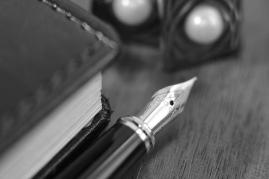 Business accessories on desktop: notebook, diary, fountain pen, cufflinks. Macro with blur and soft focus