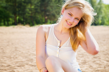 Fototapeta premium Sweet blonde young girl resting on a beach in a sunny morning