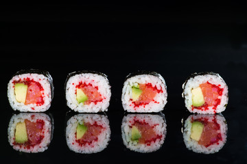 close-up of sushi with salmon and avocado on a dark background w
