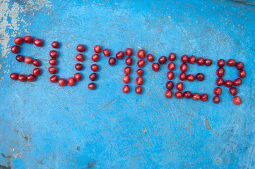 Word Summer made of cherries on textured blue background