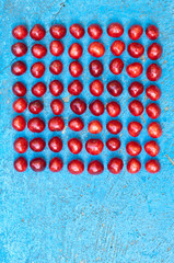 Square arrangement of ripe cherries on blue textrured background