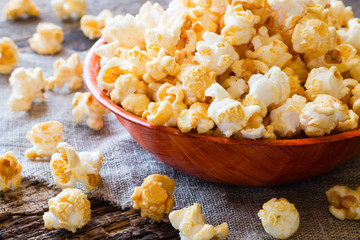 Popcorn in a bowl on a wooden background close up - obrazy, fototapety, plakaty
