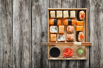 Set of sushi maki and rolls at box on wood.