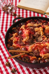 Light summer plums skillet cake on a red tablecloth in a cage with a cookbook and spices 