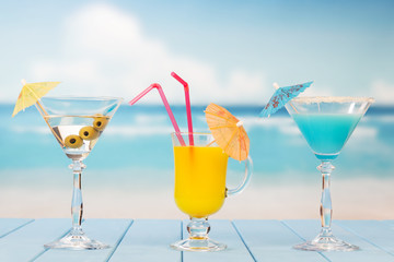 Martini glass with olives, drink and juice on background sea.