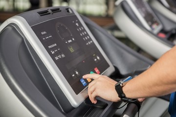 Hand pressing a button on the console display of a treadmill