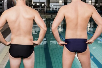 Rear view of swimmers standing by the pool