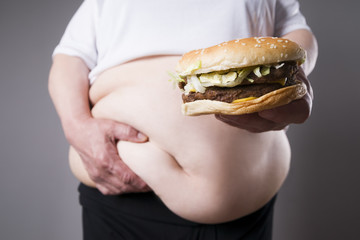 Women suffer from obesity with big hamburger in hand. Junk food concept