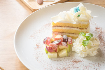 White chocolate cake and mixed fruit on white plate