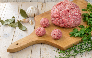 Сырое рубленное мясо, фарш с травами и чесноком на светлом деревянном фоне