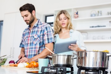Young couple chopping vegetable and using digital tablet