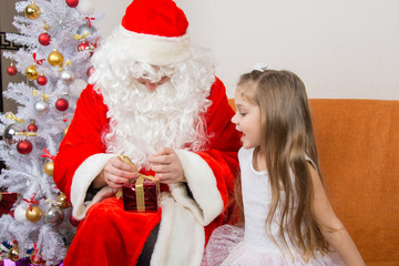 The girl with interest looks like Father Christmas helps to open her gift