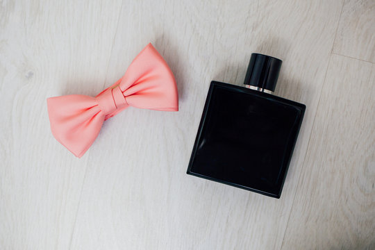Bottle of male perfume and pink bow tie on the white background