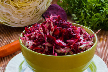 Diet salad with beetroot, carrot, cabbage, olive oil and lemon. Served in a bowl on wooden...