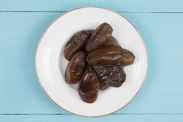 dried dates in the dish on the wood table.