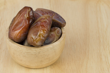 dried dates in the bowl on the wood table.