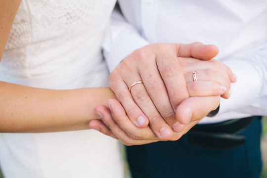 lovers holding hands with gold wedding rings