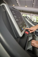 Hand of a person setting control panel of treadmill