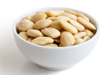 White bowl of peeled whole almonds isolated on white.