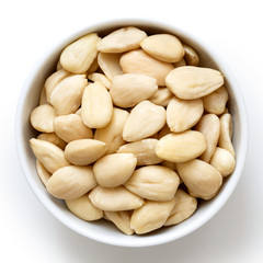 Bowl of peeled whole almonds isolated on white from above.