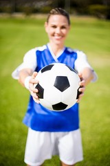 Female football player standing with ball