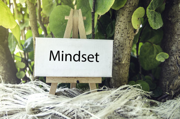 conceptual image, Mindset word on white canvas and wooden easel.Green nature background and sunlight effect