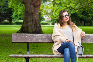 Beautiful smiling girl sitting on the bench in the park