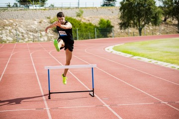 Athlete jumping above the hurdle