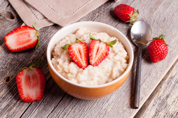 Tasty oatmeal with strawberry on table close-up