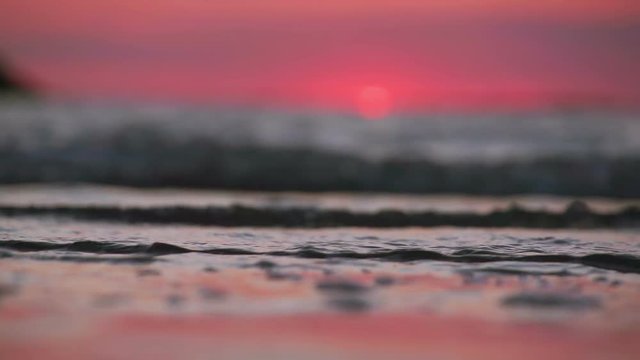 Perfect Sunset Beach With Waves Lapping On To The Sandy Shore. Deep Red Sky Filmed In Super Slow Motion