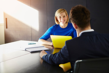 Colleagues sitting at desk having meeting smiling