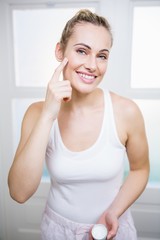 Fototapeta na wymiar Young woman applying cream on face