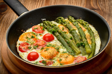 Fried eggs with green asparagus and tomatoes.