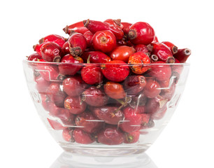 Are dry dog rose berries in glass bowl on white .