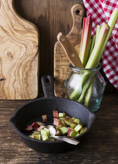 bundle of rhubarb stalks and slices  a kitchen knife on  wooden cutting board, selected focus