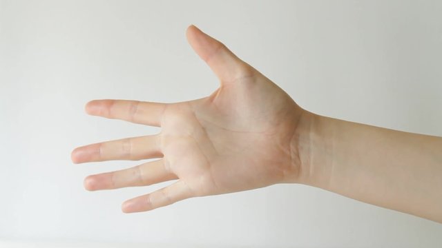 Woman's hand doing game rock paper scissors against white background