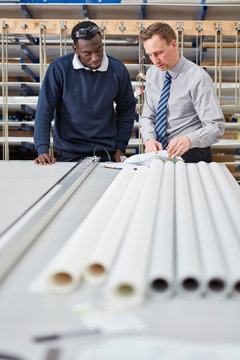 Manager and factory worker checking paperwork in roller blind factory