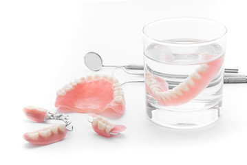 Set of Denture in glass of water and tools  on white background