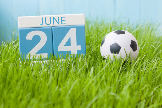 June 24th. Image of june 24 wooden color calendar on green grass background with football outfit. Summer day