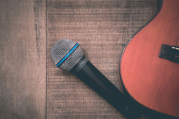 Close-up of grunge ukulele and microphone on wooden background
