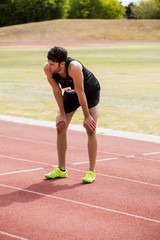 Tired athlete standing on running track