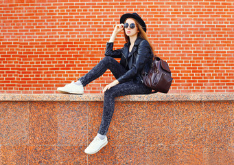 Fashion pretty woman in black rock style sitting in city over br